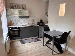 A compact kitchen with a built-in oven, a microwave, and a sink. There's a small dining area with a table and chairs.