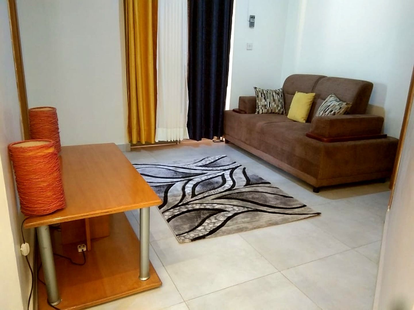 Una sala de estar con un sofá, un tapete estampado y una mesa con un ovillo de hilo.