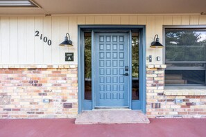 A blue door with a grid pattern, a brick wall, and a number '2100' on the wall. - Cozy 2BR, Steps to Mines, Workspaces (Golden)