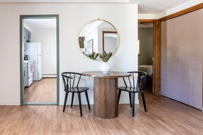 A dining area with a round table, two chairs, a mirror, and a potted plant. - Cozy 2BR, Steps to Mines, Workspaces (Golden)