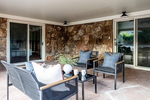 An outdoor seating area with wicker furniture and a stone wall backdrop. - Cozy 2BR, Steps to Mines, Workspaces (Golden)