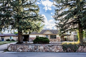 A residential house with a stone foundation, a garage, and a covered porch. - Cozy 2BR, Steps to Mines, Workspaces (Golden)