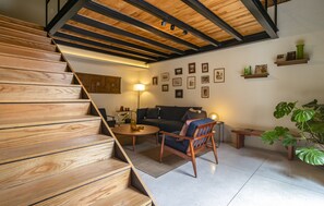 A staircase with wooden steps leading to a living area with a sofa, a coffee table, and a lamp. - Emilio Dondé Apartment in Downtown Mexico City (Ciudad de México)