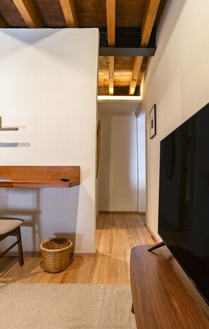 Ein modernes Interieur mit einer hölzernen Bank, einem Fernseher und einem Korbwannenmöbel.