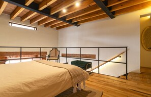 Ein Schlafzimmer mit einem Bett, einem Sessel, einem kleinen Tisch und einer Treppe.