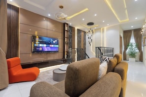 A modern living room with a flat-screen TV, a sofa, a coffee table, and a staircase. - Luxury 2BR in Lagos  Wood-Slat Accent Design, AC & Modern Comfort (Lagos)