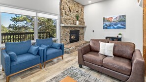 A living room with a stone fireplace, two sofas, a rug, and a painting on the wall. - Deer Mountain Retreat 3bdr townhouse near Fall RiverRocky Mountain National Park (Estes Park)