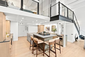 Une cuisine moderne dotée d’un îlot central, de tabourets de bar et d’un escalier menant à un niveau supérieur.