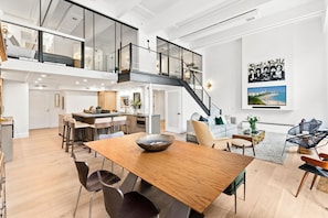 Un appartement-loft spacieux comprenant un coin repas, une cuisine et un balcon doté d’une balustrade en verre.