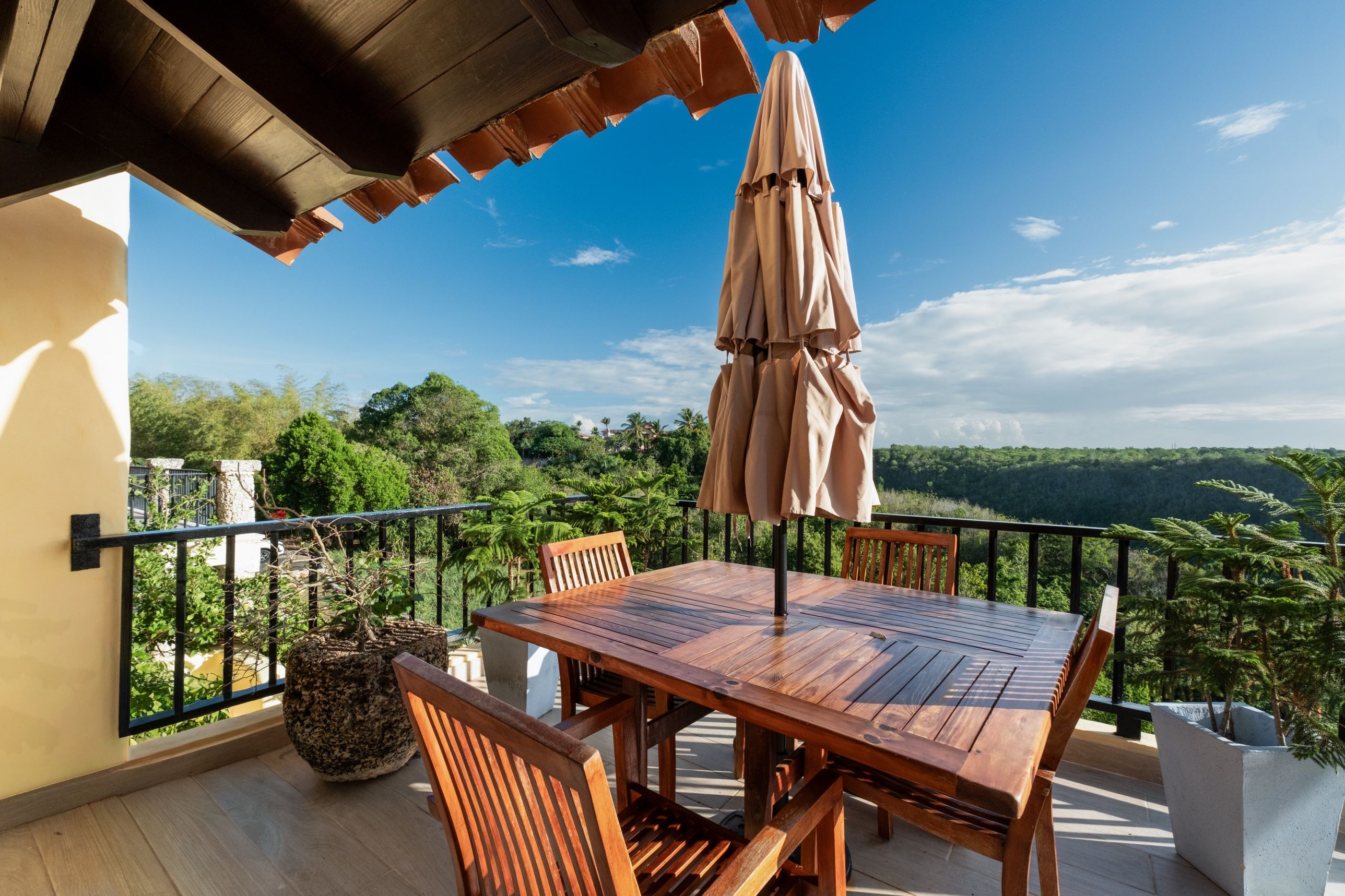 Una mesa y sillas de madera en un balcón con vistas a un paisaje boscoso.