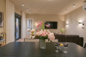 A dining area with a table set for two, a vase of flowers, and a bowl of fruit. - Villa Belo Krug – Heated Pool & Sea View (Jesenice)