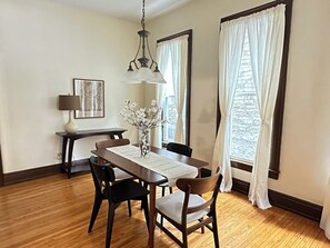 A dining area with a wooden table, chairs, a vase with flowers, a lamp, and a framed picture on the wall. - Entire Historic Elmwood Village 3BR APT - Amazing Location (Buffalo)