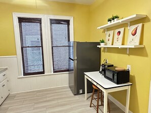 Une cuisine compacte équipée d’un réfrigérateur, d’un four à micro-ondes et d’une petite table.