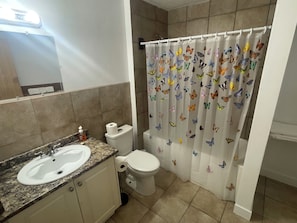 A bathroom with a sink, toilet, and shower curtain with butterfly patterns. - Bayside Inn (Alert Bay)
