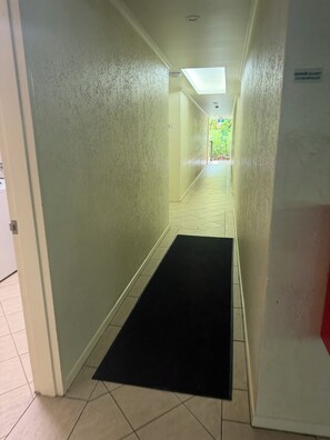 Ein Hotelgang mit schwarzer Matte am Eingang, Fliesenboden und einem Oberlicht.