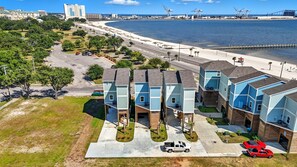 A residential area with modern houses, a beach, and a port in the background. - Beachfront Paradise 3BR/3BA Park & Casino (Gulfport)