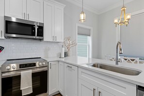 A modern kitchen with stainless steel appliances, white cabinetry, and pendant lighting. - Beachfront Paradise 3BR/3BA Park & Casino (Gulfport)