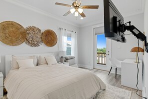 Quarto com cama, escrivaninha, televisão e arte decorativa na parede.