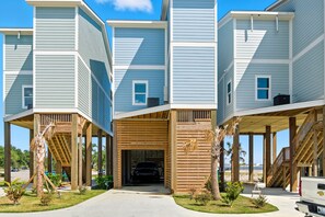 A modern multi-story residential building with a covered entrance and a driveway leading to a parking area. - Beachfront Paradise 3BR/3BA Park & Casino (Gulfport)