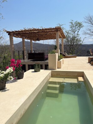 Eine Dachterrasse mit Pergola, Sitzgelegenheit und einem kleinen Pool.