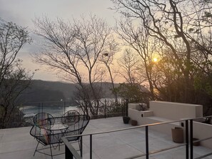 A terrace with outdoor seating, overlooking a body of water and hills. - Luxury Villa Xololo on the secluded beach of La Boquilla, Oaxaca, Pacific Coast (San Pedro Pochutla)