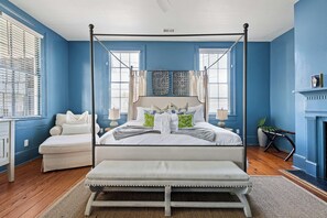 Een slaapkamer met een hemelbed, een bankje en een open haard.