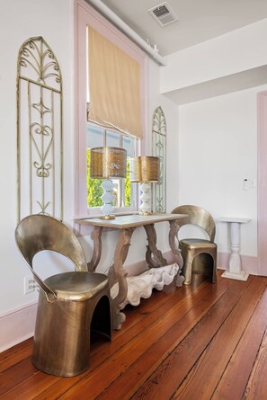 Een eetgedeelte met een houten tafel, twee stoelen en een raam met gordijnen.