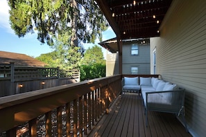 A wooden deck with a built-in seating area, a railing, and string lights. - Capitol Hill 2BR Gem - Stroll to Parks & Cafés (Seattle)