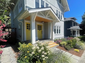A two-story house with a porch and a front yard. - Capitol Hill 2BR Gem - Stroll to Parks & Cafés (Seattle)
