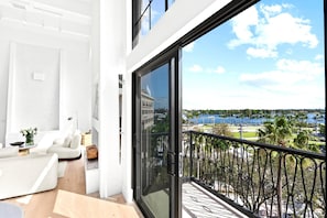 Ein modernes Wohnzimmer mit Balkon und Blick auf einen Yachthafen und Stadtpanorama.