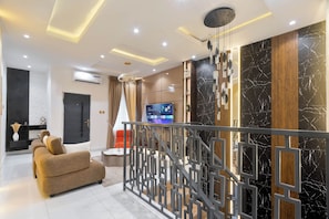A modern living room with a sofa, a TV, and a decorative wall. - Charming 3-bedroom apartment with AC in  Lagos (Lagos)