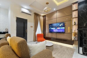 A modern living room with a flat-screen TV, a sofa, a coffee table, and a decorative wall unit. - Charming 3-bedroom apartment with AC in  Lagos (Lagos)