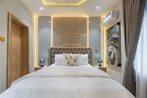 A modern hotel room with a large bed, a headboard with a tufted design, and a wall-mounted air conditioning unit. - Charming 3-bedroom apartment with AC in  Lagos (Lagos)