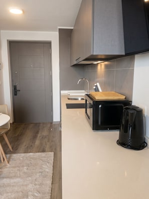 A modern kitchen with a built-in oven, a coffee maker, and a wooden cutting board. - Edificio Froilan Lagos by Domus Travels (La Florida)