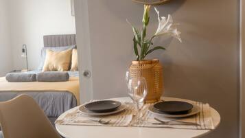 Un comedor con una mesa redonda, sillas, un florero con flores y un espejo en la pared.