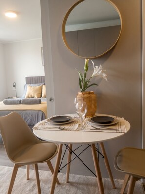 A dining area with a round table, chairs, a vase with flowers, and a mirror on the wall. - Edificio Froilan Lagos by Domus Travels (La Florida)
