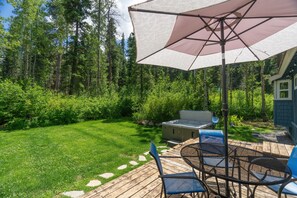 Une terrasse aménagée avec du mobilier d’extérieur, un jacuzzi et un parasol.
