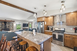 A modern kitchen with granite countertops, stainless steel appliances, and wooden cabinetry. - Homewood Cabin  - Walk to the Lake - Pet Friendly (Homewood)