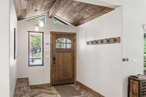 A wooden door with a window, a wall-mounted light fixture, and a coat rack. - Homewood Cabin  - Walk to the Lake - Pet Friendly (Homewood)