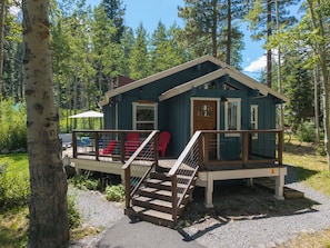 A cabin with a porch, red chairs, and a staircase leading to the entrance. - Homewood Cabin  - Walk to the Lake - Pet Friendly (Homewood)