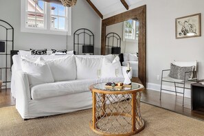 Een moderne woonkamer met een witte bank, een ronde houten salontafel en een grote spiegel.