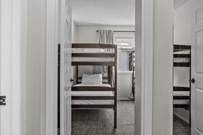 A bunk bed room with a window and a door. - Mountain Retreat | 3BR | Walk to Downtown (Canmore)