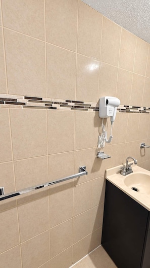 A bathroom with beige tiles, a hairdryer mounted on the wall, a hand dryer, and a sink with a faucet. - Bowra Suite Privada 7, Colonia Americana (Guadalajara)