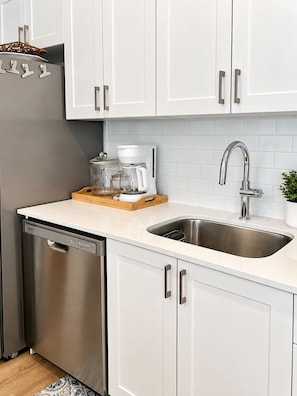 Een moderne keuken met witte kasten, roestvrijstalen apparatuur en een inbouwvaatwasser.