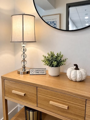 Een houten bureau met een lamp, een bordje met de uitschrijf-tijd, een potplant en een decoratieve pompoen.