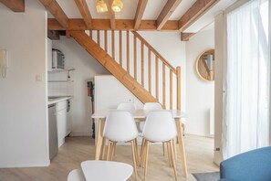 A modern kitchen with white cabinets and a wooden staircase. - Duplex lumineux avec balcon et parking (Vannes)