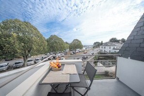 A balcony with a table, chairs, and a basket of bread and fruit. - Duplex lumineux avec balcon et parking (Vannes)