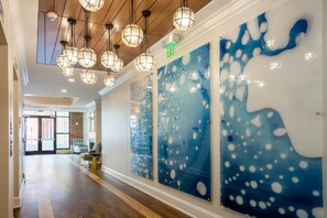 A hallway with wooden flooring, hanging pendant lights, and abstract wall art. - BLOCK King 583 - 2br (Charleston)