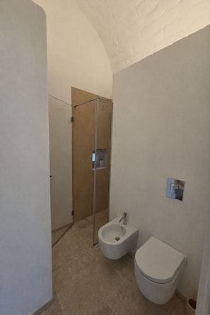 Un baño pequeño con inodoro, bidé y cabina de ducha.