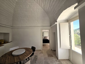 Un pasillo estrecho que lleva a un dormitorio, con un área de comedor que incluye una mesa redonda y sillas.